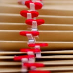 Natural-colored wedding programs with red heart clips assembled at the ceremony.