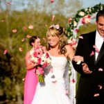 Bride and groom are showered with rose petals from their guests following the wedding ceremony.