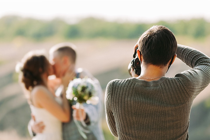 Wedding photographer captures the bride and groom kissing at a sun-filled outdoor wedding.