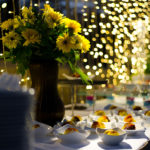 Sunflowers, draped lighting and a dessert course on the table at an outdoor rehearsal dinner.