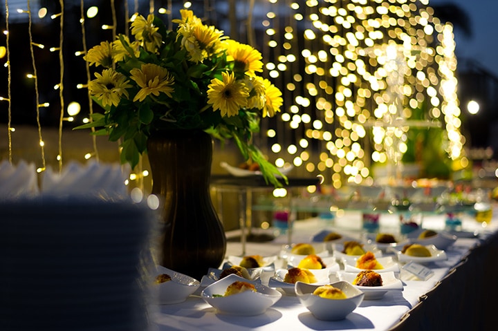 Sunflowers, draped lighting and a dessert course on the table at an outdoor rehearsal dinner.