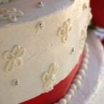 White wedding cake with red stripe, floral design silver touches.