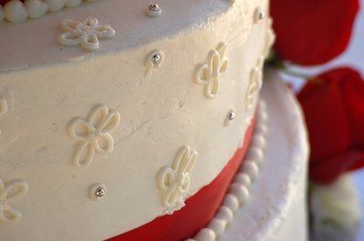 White wedding cake with red stripe, floral design silver touches.