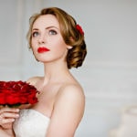 Beautiful bride with a red rose bouquet warring a rose in her hair.