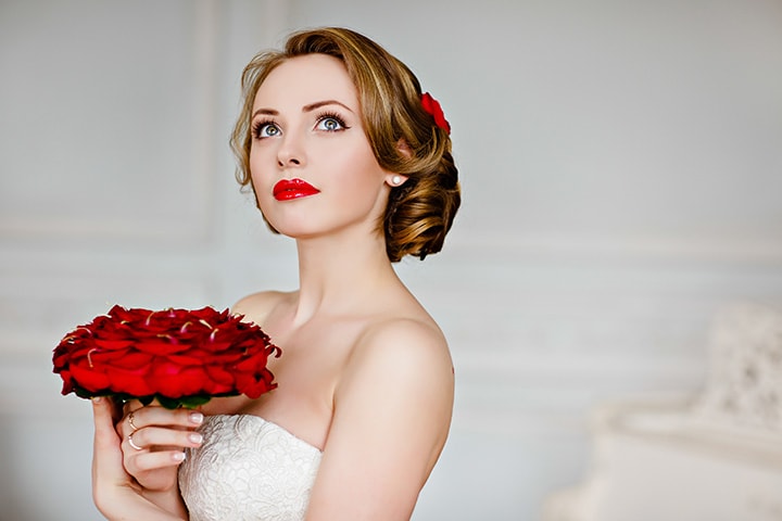 Beautiful bride with a red rose bouquet warring a rose in her hair.