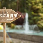 Rustic wooden wedding sign with a heart at an outdoor wedding.