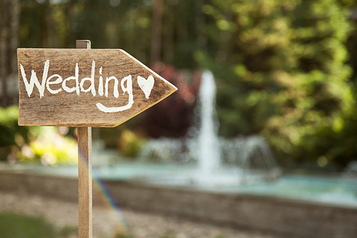 Rustic wooden wedding sign with a heart at an outdoor wedding.