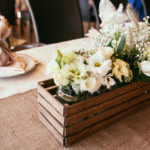 Rustic floral boxes serve as reception centerpieces at a rustic-themed wedding event.
