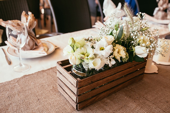 Rustic floral boxes serve as reception centerpieces at a rustic-themed wedding event.