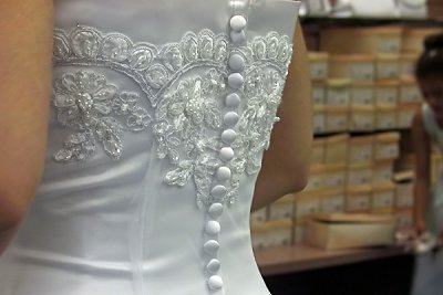 Bride shops for shoes to match her white satin and lace wedding gown.