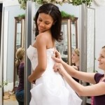 A seamstress helps make the final adjustments to the bride's gown before her wedding.