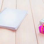 Wedding planning journal on a light wood tabletop with festive wrapped gift favors.