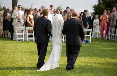 Bride approaches her adoring guests at an outdoor wedding ceremony.