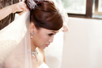 Bride gets the final touches added to her wedding day hairstyle, including the veil.