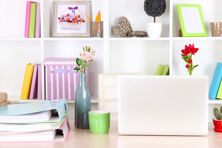 Wedding planning workspace with colorful binders and shelving.