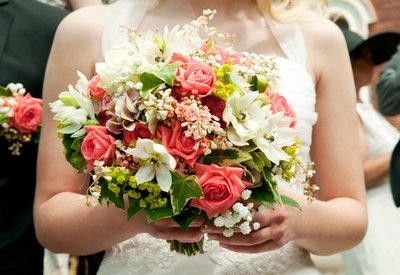 Bride carries a pink, green and white floral bouquet after the wedding ceremony.