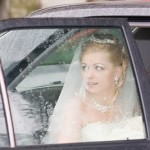 A bride looks out at her ceremony venue as she arrives by car on her wedding day.