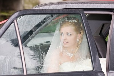 A bride looks out at her ceremony venue as she arrives by car on her wedding day.
