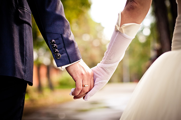 Bride and groom walking hand in hand outdoors.