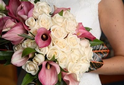 Bride carries her bouquet of ivory roses and light mauve calla lilies.