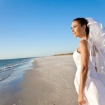 Beautiful bride looks out across the ocean after her wedding ceremony.