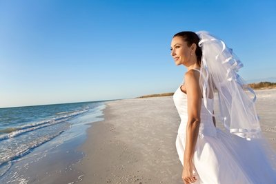 Beautiful bride looks out across the ocean after her wedding ceremony.
