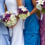 Bride poses with her bridesmaids in complementary dress shades.