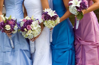 Bride poses with her bridesmaids in complementary dress shades.