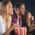 Young happy couple at the movies eating popcorn.