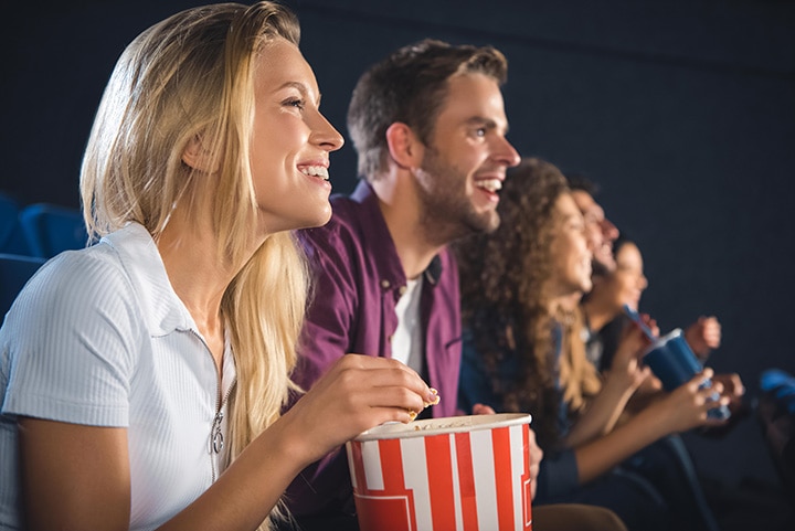 Young happy couple at the movies eating popcorn.