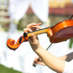 Violinist performing prelude music at an outdoor wedding ceremony.