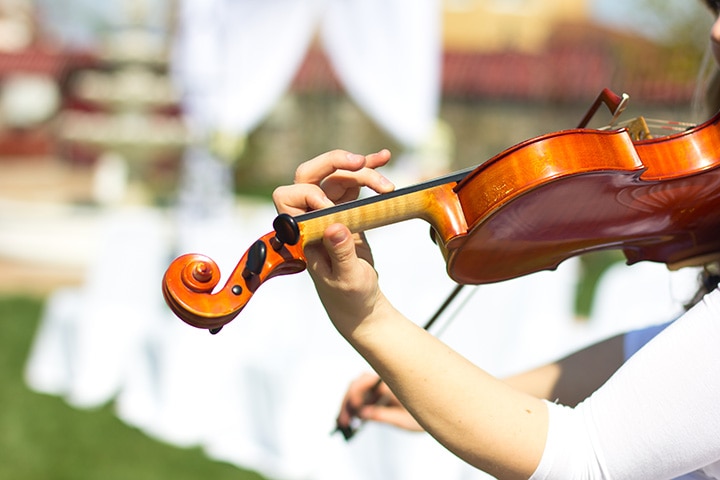 Violinist performing prelude music at an outdoor wedding ceremony.